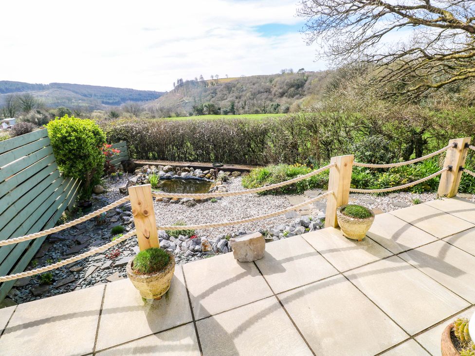 A garden with a patio and a pond at No.51 Llanteg Park Amroth