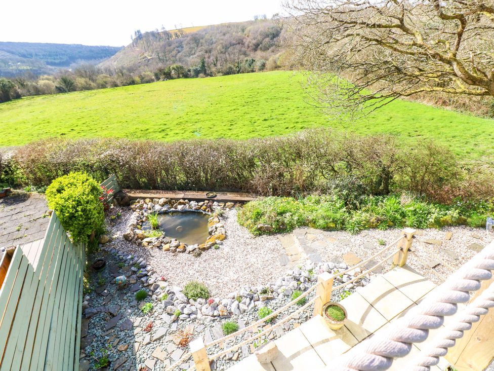 A garden with a pond surrounded by rocks and grass at No.51 Llanteg Park in Amroth
