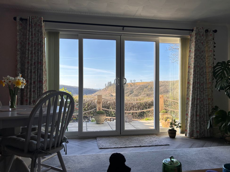 A dining room with sliding doors and a view of the outdoor landscape at No.51 Llanteg Park Amroth