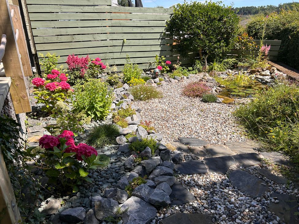 A garden with flowers and stones at 51 Llanteg Park Amroth