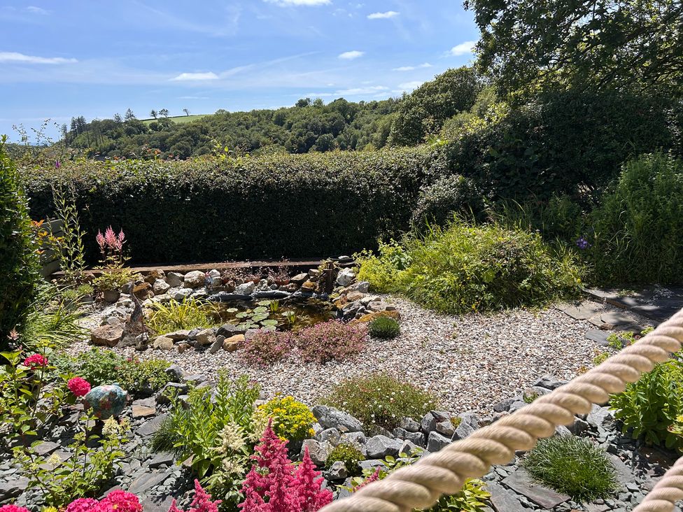 A garden with flowers and a pond at 51 Llanteg Park Amroth