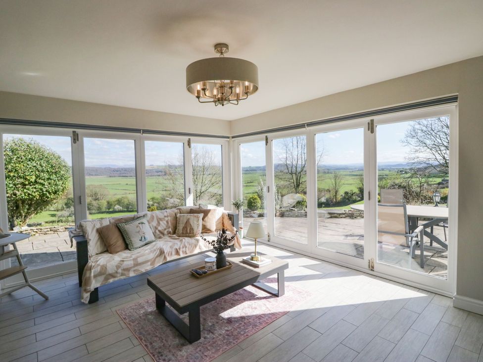 A sunroom with a sofa and coffee table at Barn Howe in Lyth near Levens