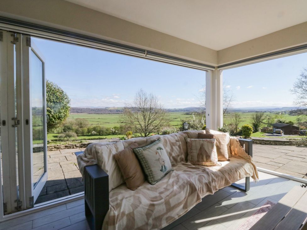 A conservatory with a sofa and outdoor view at Barn Howe Lyth near Levens