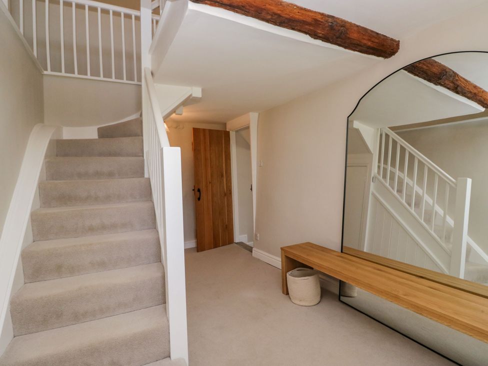 A hallway with a staircase, mirror, and wooden bench at Barn Howe, Lyth near Levens