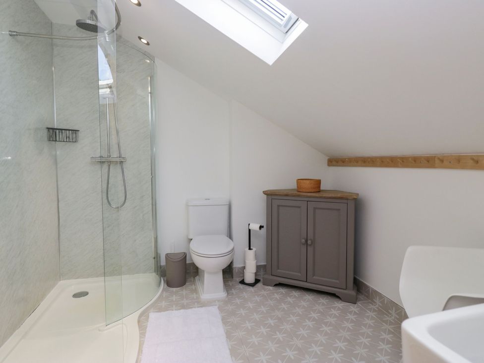 A bathroom with a shower, toilet, and cabinet at Barn Howe in Lyth near Levens