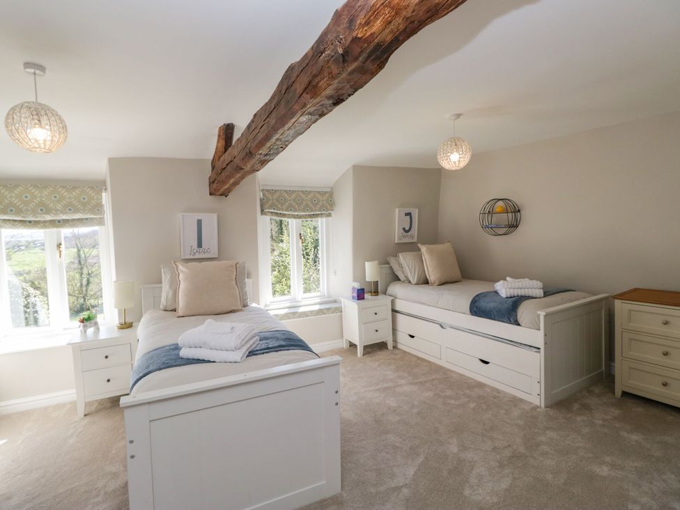 A bedroom with two beds and windows at Barn Howe Lyth near Levens