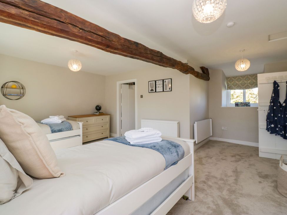 A bedroom with two beds and a dresser at Barn Howe Lyth near Levens