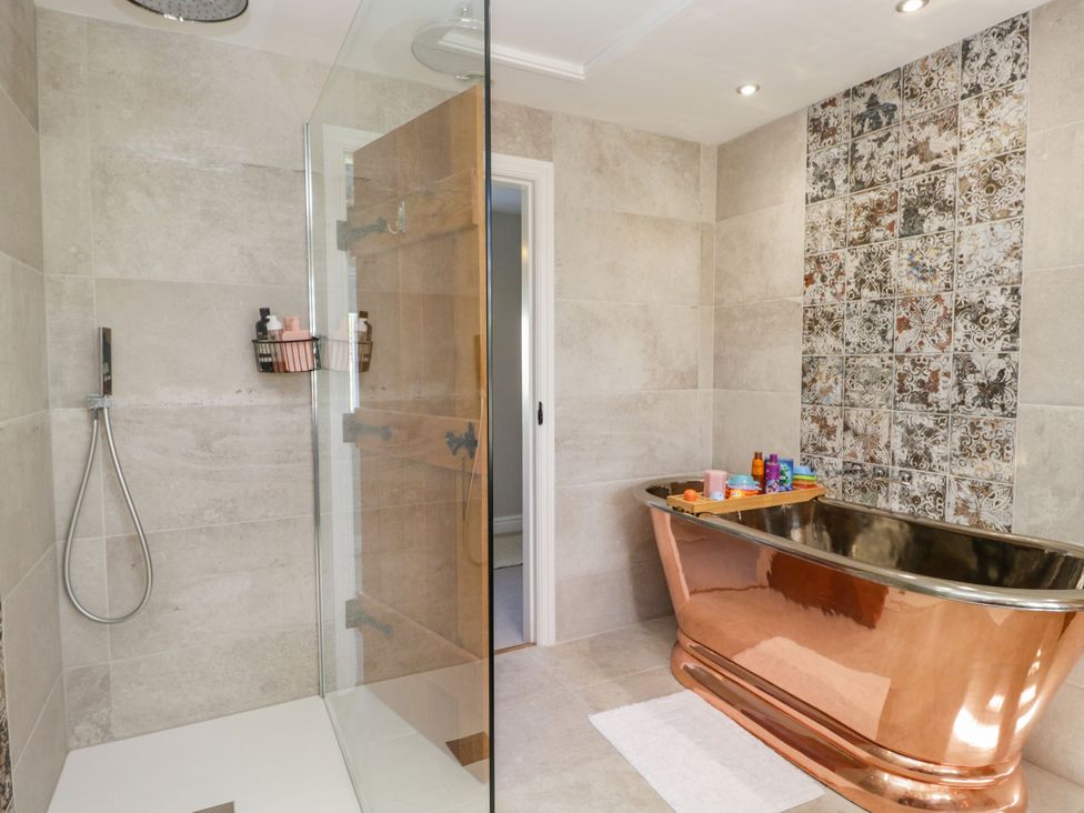 A bathroom with a glass shower and a copper bathtub at Barn Howe in Lyth near Levens