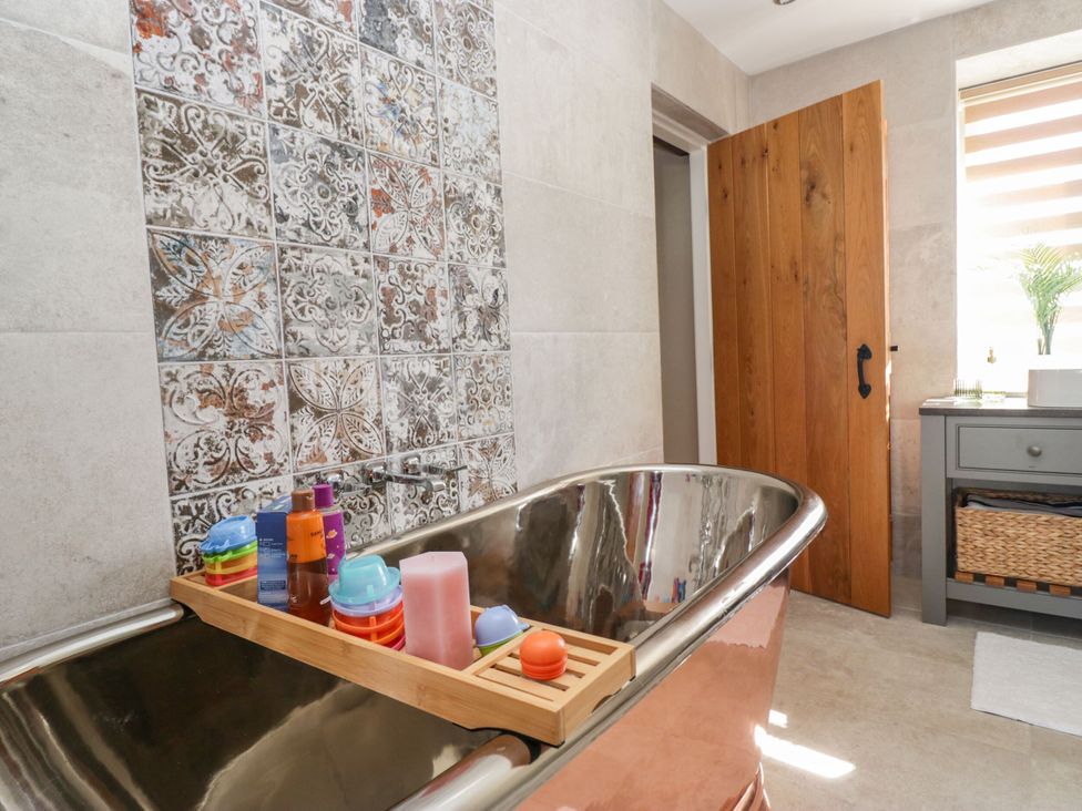 A bathroom with a bathtub and wooden tray at Barn Howe Lyth near Levens