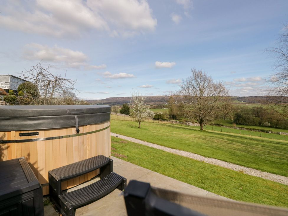 An outdoor area with a hot tub and view of trees and fields at Barn Howe Lyth near Levens