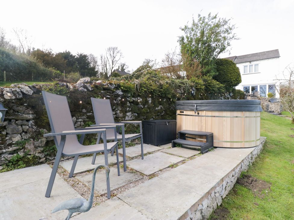 A garden with two chairs and a hot tub at Barn Howe Lyth near Levens