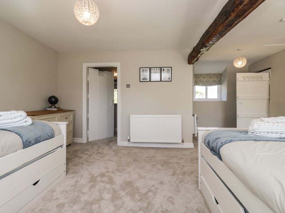 A bedroom with two beds and a dresser at Barn Howe in Lyth near Levens