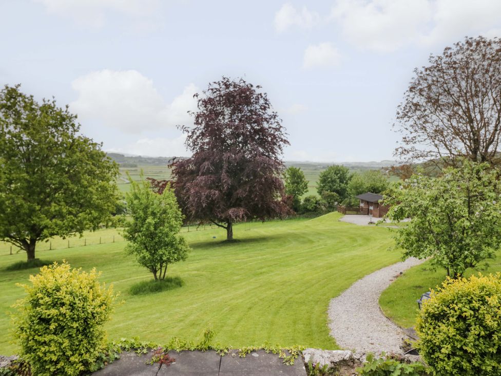 A garden with trees, grass, and a path at Barn Howe in Lyth near Levens