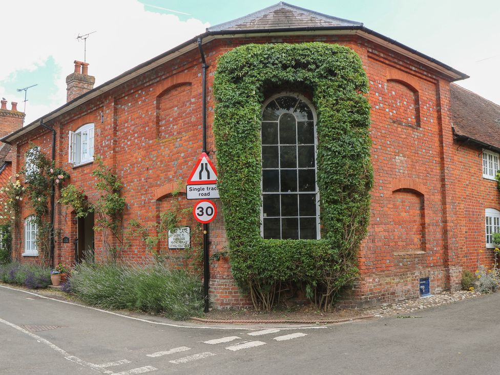 A brick building with a large window and plants outside at Flat 1 in Winchester