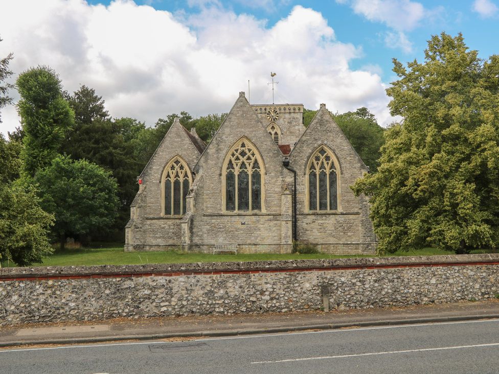 A stone building with gothic windows and trees at Flat 1 in Winchester