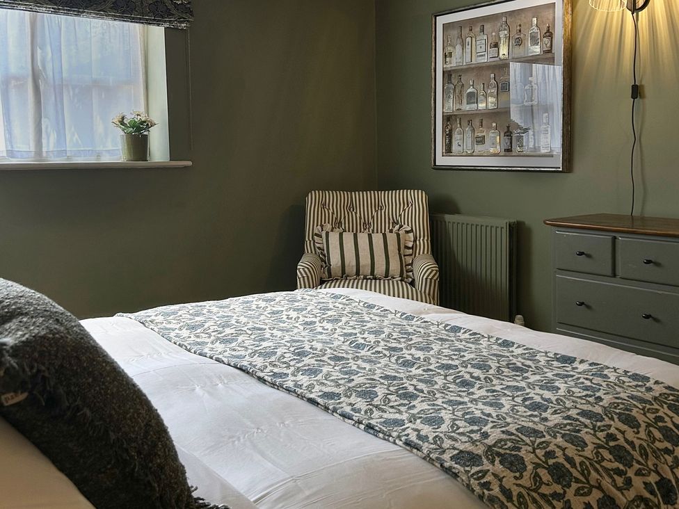 A bedroom with a bed and striped chair at Skylarks Winchester