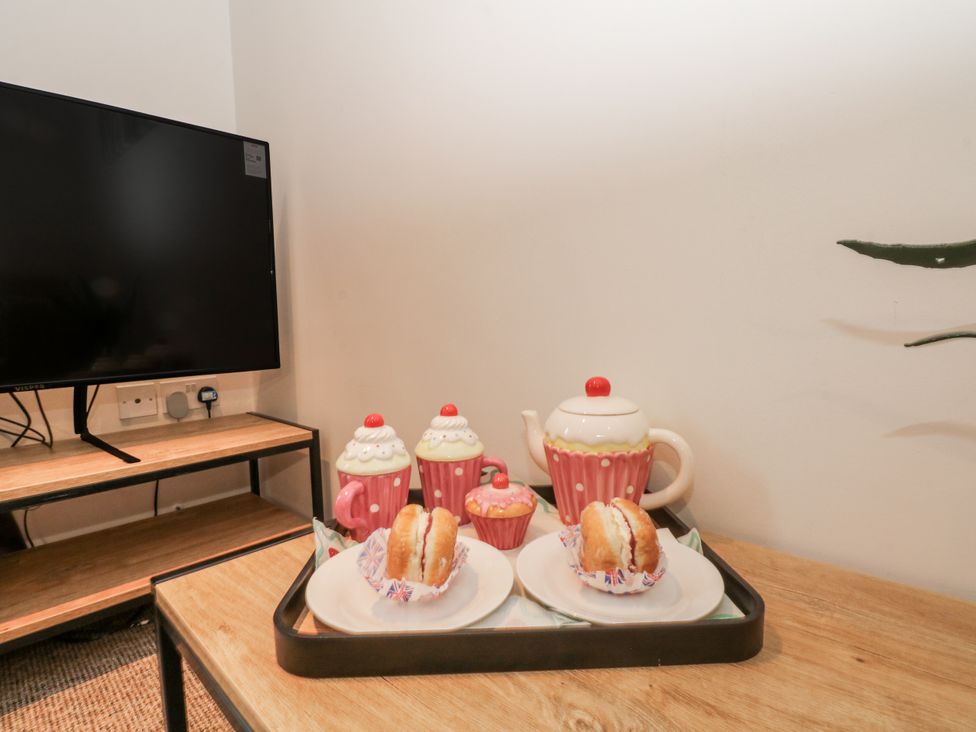 A living room with a television and tea set at 5 The Old Coach House in Chinley