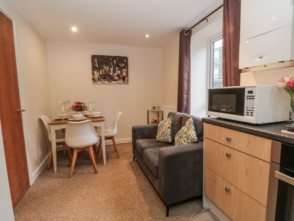 A kitchen with dining area and sofa at 5 The Old Coach House in Chinley
