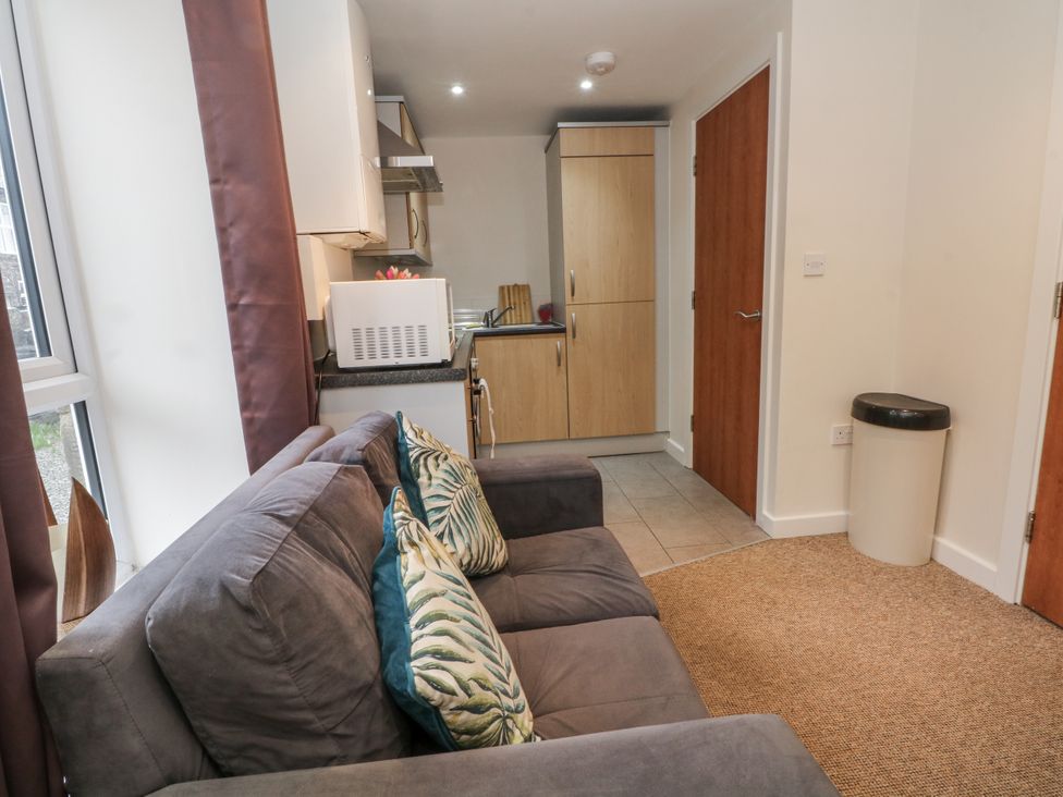 A living room with a sofa and kitchen cabinets at 5 The Old Coach House in Chinley
