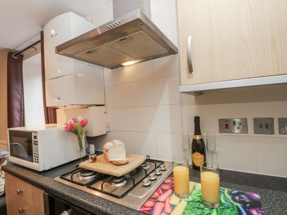 A kitchen with a stove, microwave, and juice on the counter at 5 The Old Coach House Chinley