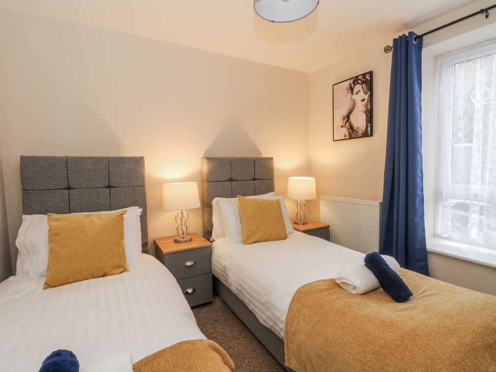 A bedroom with two single beds and a window at 5 The Old Coach House Chinley