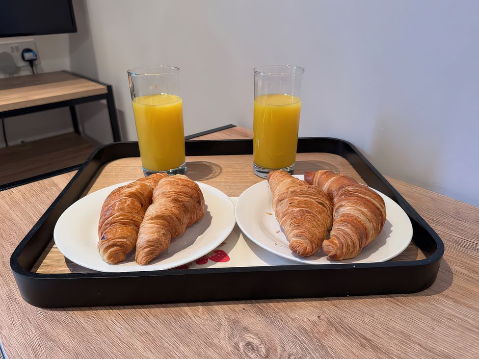 A tray with croissants and orange juice on a table at 5 The Old Coach House Chinley
