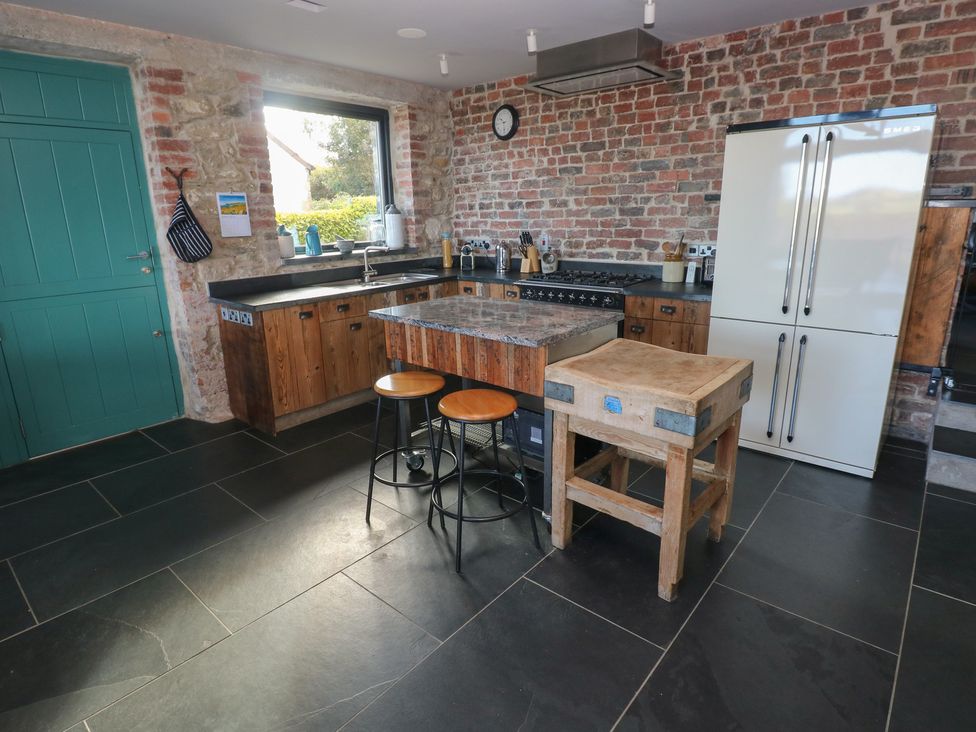 A kitchen with wooden counter and stools at The Barn in Newport