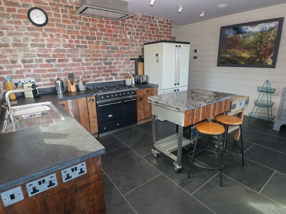 A kitchen with a stove, sink, and island at The Barn in Newport