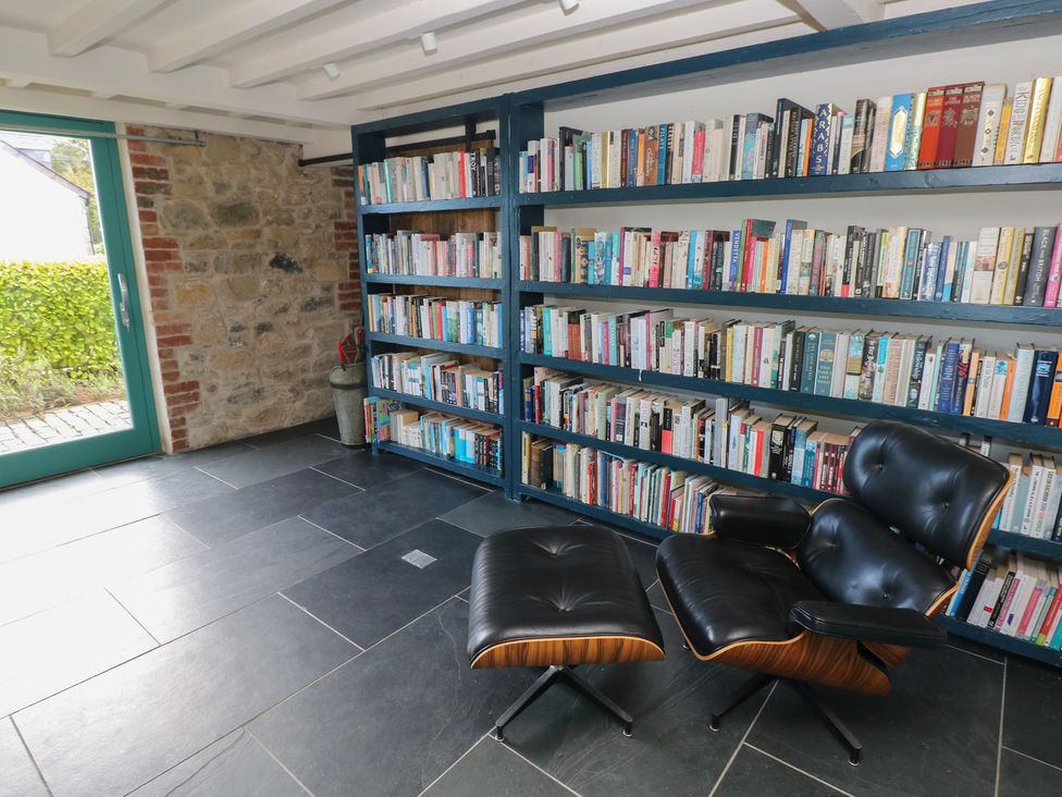 A reading room with a bookshelf and chair at The Barn in Newport