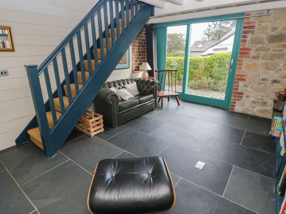 A living room with a sofa and staircase at The Barn in Newport