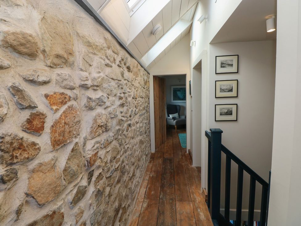A hallway with a stone wall and wooden floor at The Barn in Newport
