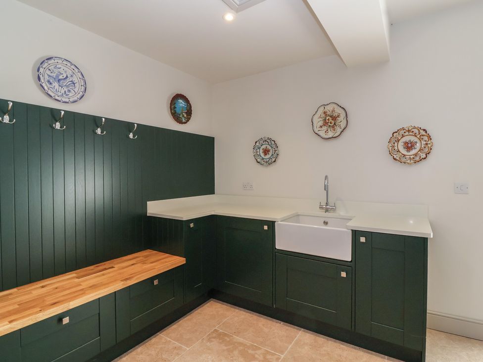 A utility room with cabinets and a sink at Leafield Cottage in Brockworth