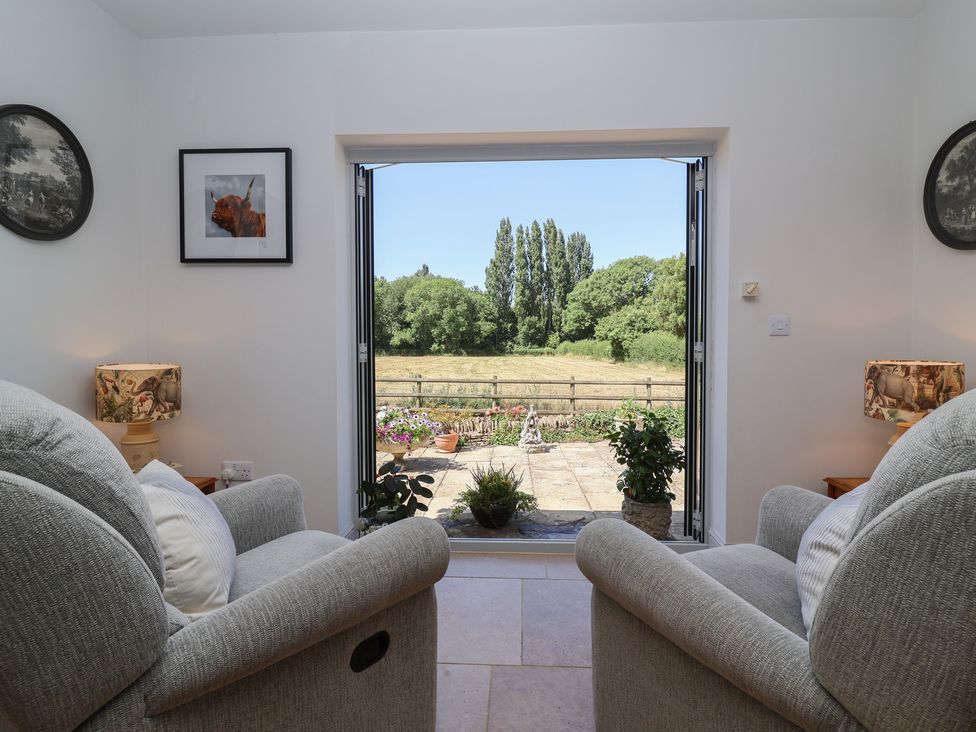 A living room with seating and a view of the countryside at Leafield Cottage in Brockworth