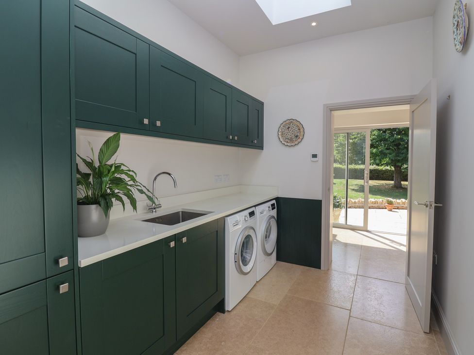 A laundry room with a washing machine and sink at Leafield Cottage in Brockworth