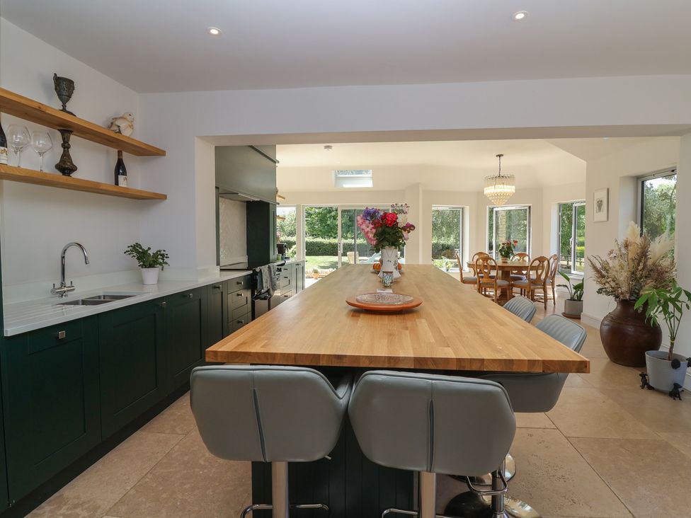 A kitchen with a central island and dining area at Leafield Cottage in Brockworth