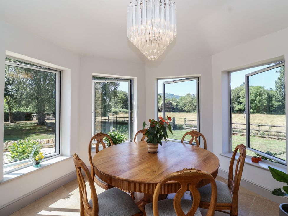 A dining room with a round table and chairs at Leafield Cottage in Brockworth