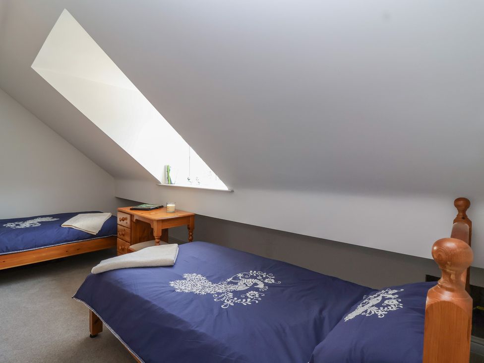A bedroom with two beds and a bedside table at Leafield Cottage, Brockworth