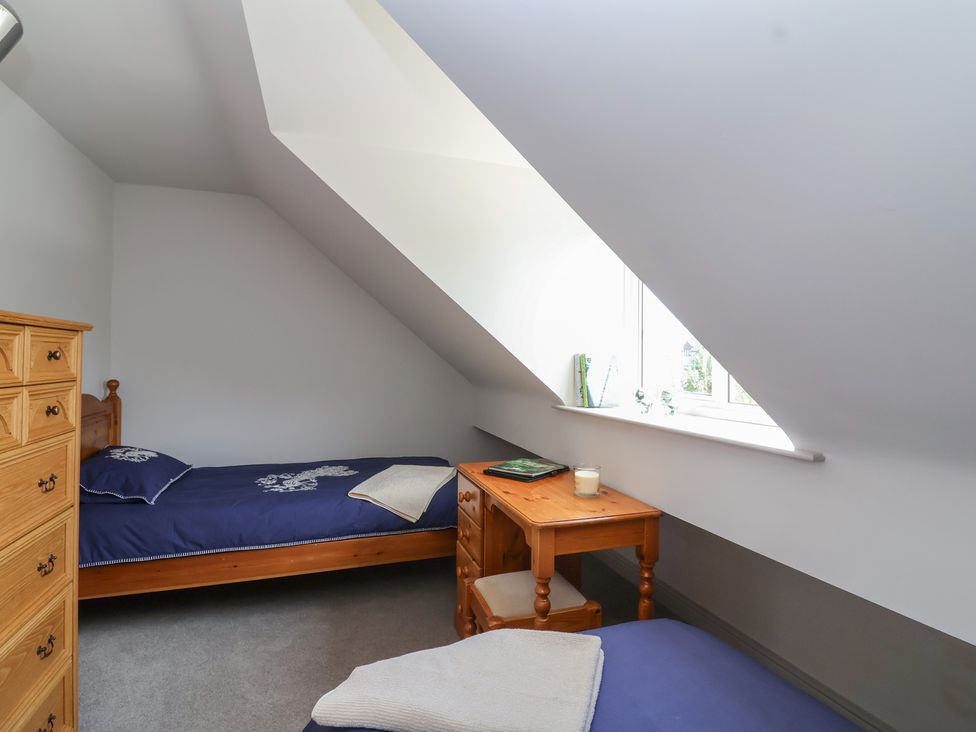A bedroom with two beds and a wooden table at Leafield Cottage in Brockworth