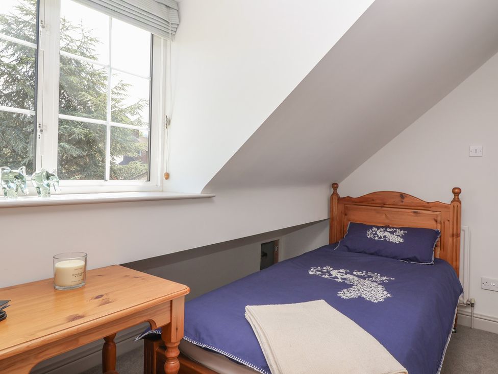 A bedroom with a single bed and a window at Leafield Cottage in Brockworth