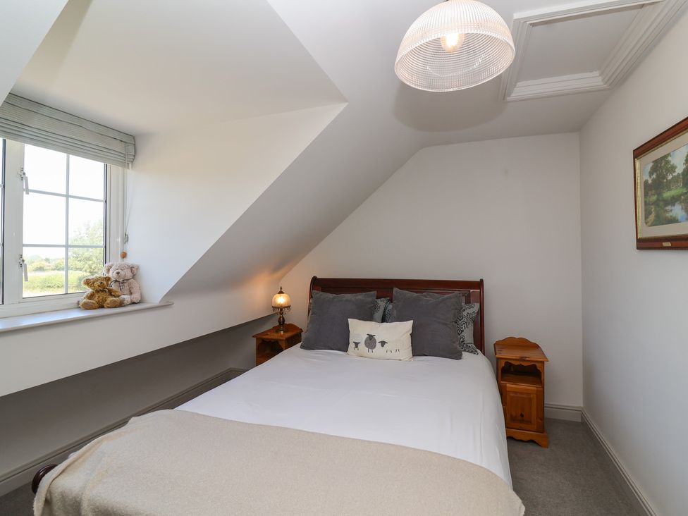 A bedroom with a bed, pillows, and a nightstand at Leafield Cottage in Brockworth
