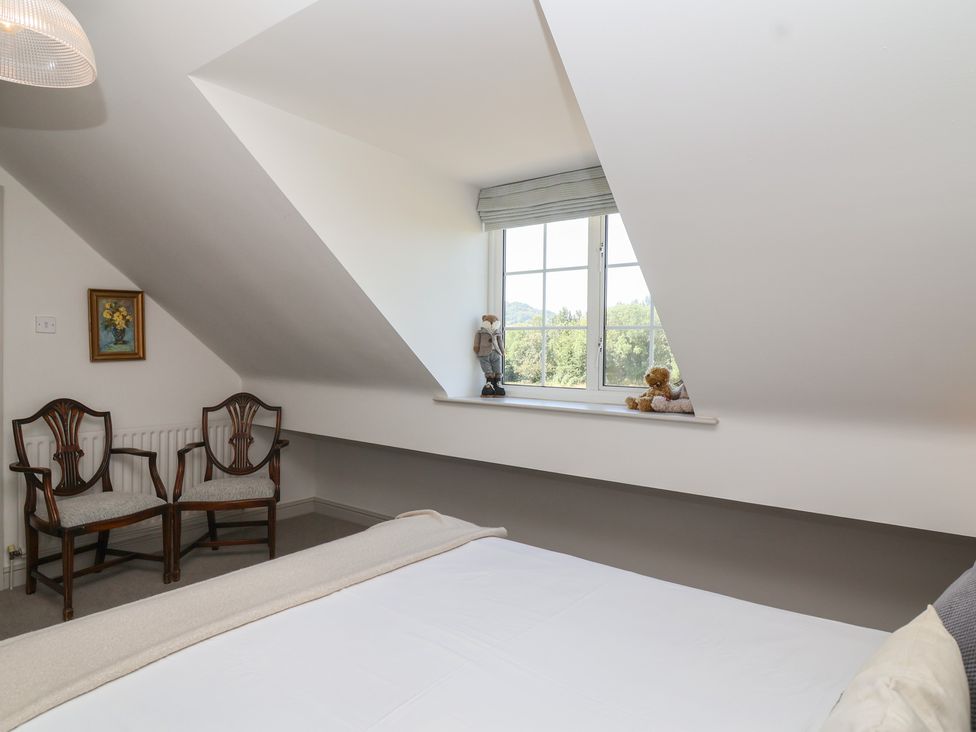 A bedroom with a window and two chairs at Leafield Cottage in Brockworth