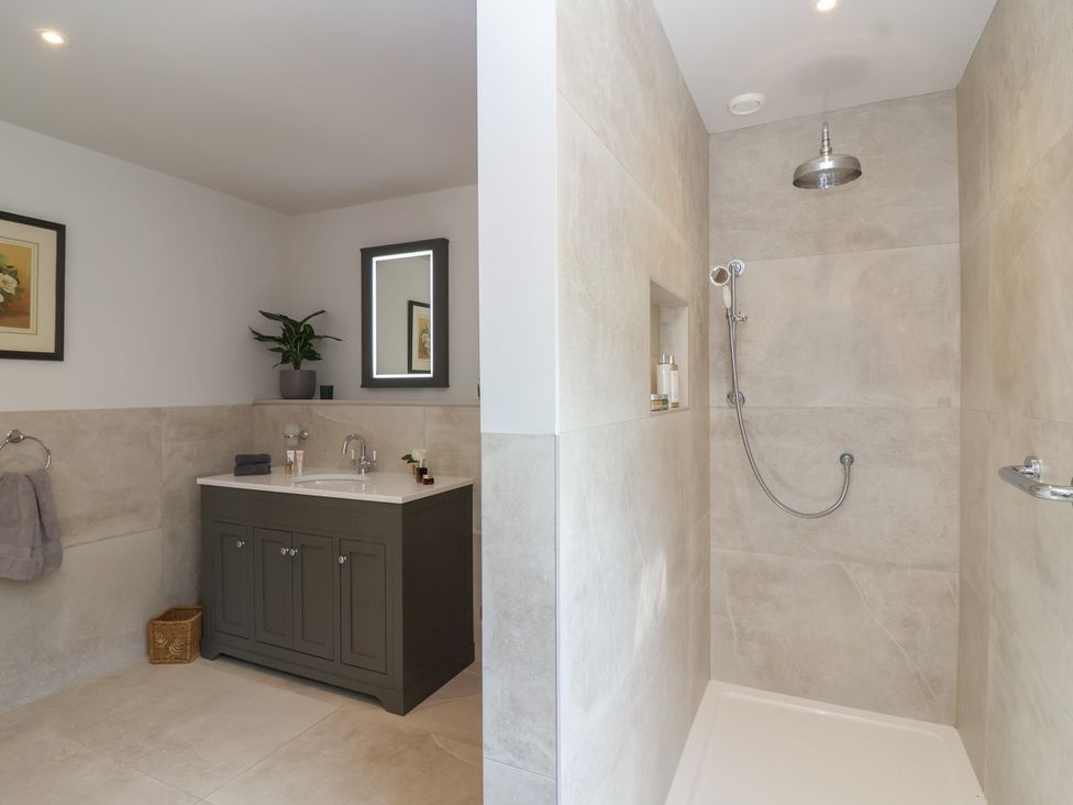 A bathroom with a shower and vanity at Leafield Cottage in Brockworth