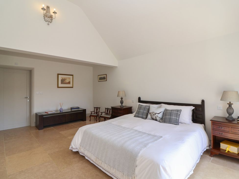 A bedroom with a bed and lamps at Leafield Cottage in Brockworth