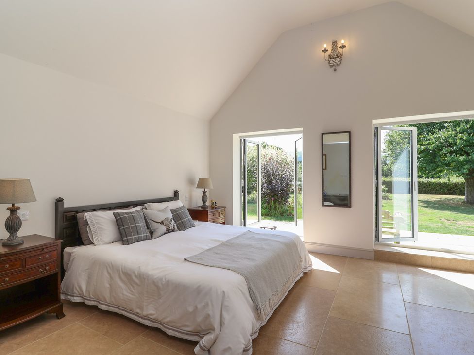 A bedroom with a bed and nightstand at Leafield Cottage in Brockworth