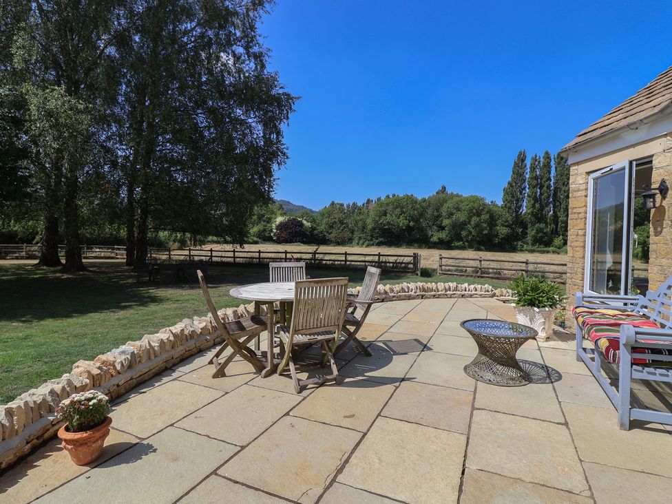 An outdoor patio with a table and chairs at Leafield Cottage in Brockworth