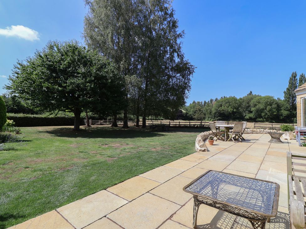 A garden with trees and patio furniture at Leafield Cottage in Brockworth