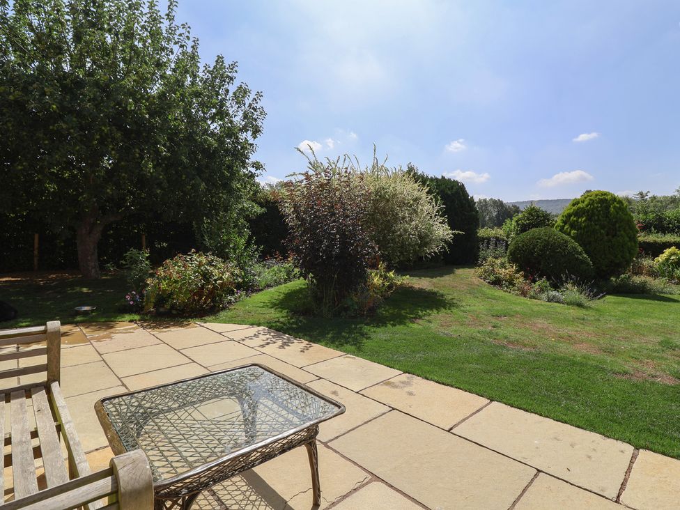 A garden with a table and seating at Leafield Cottage in Brockworth