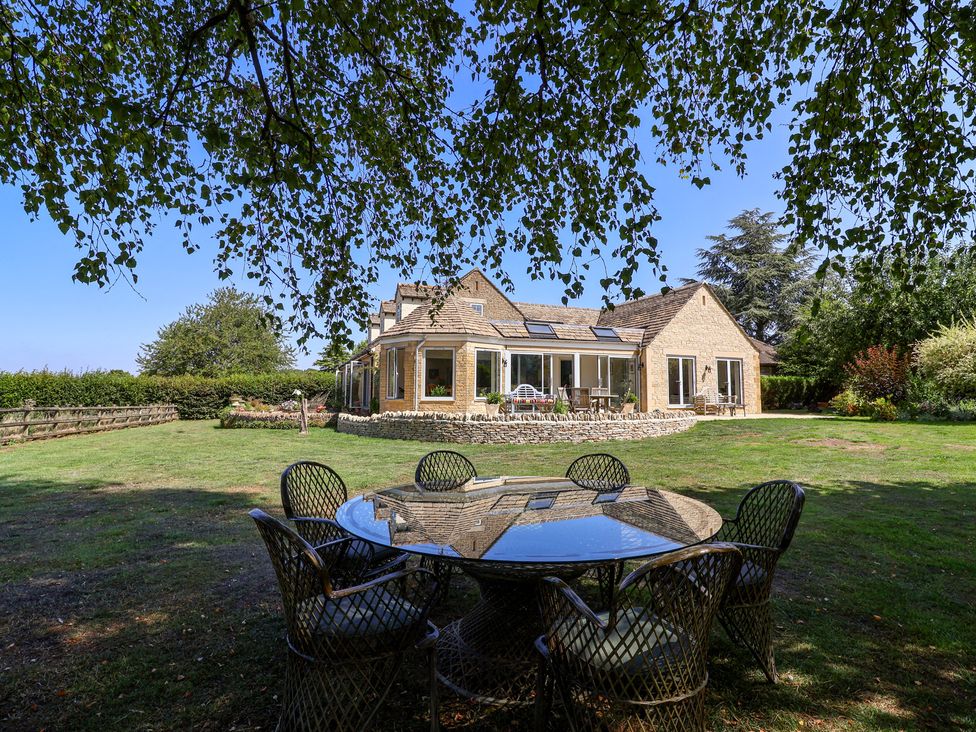 A house with a table and chairs in the garden at Leafield Cottage Brockworth