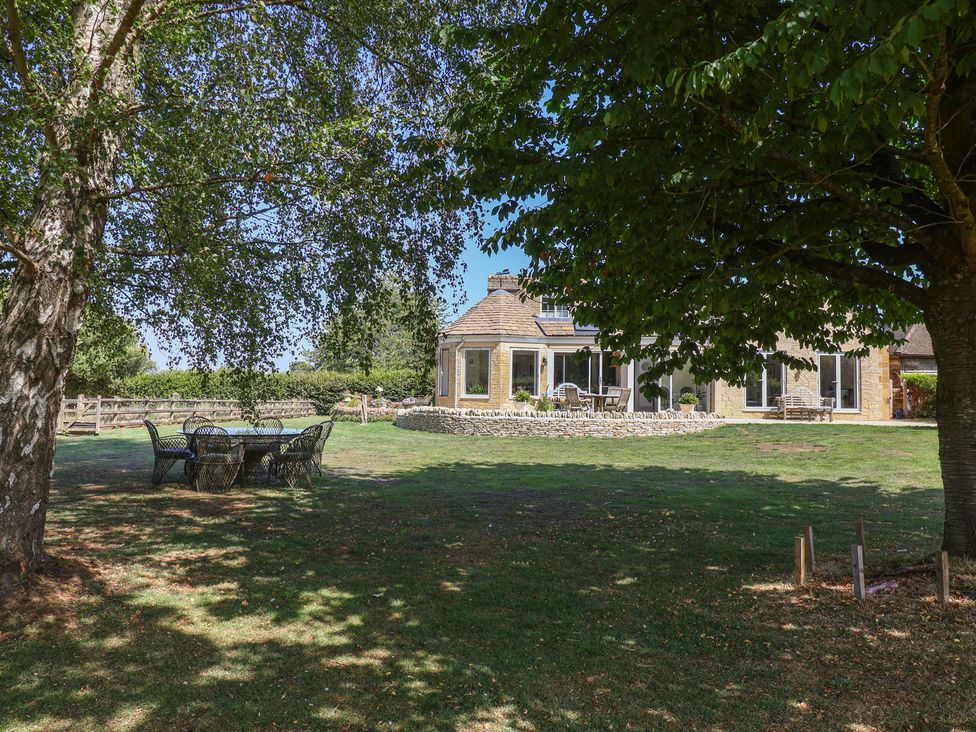 A garden with a table and chairs near a house at Leafield Cottage in Brockworth