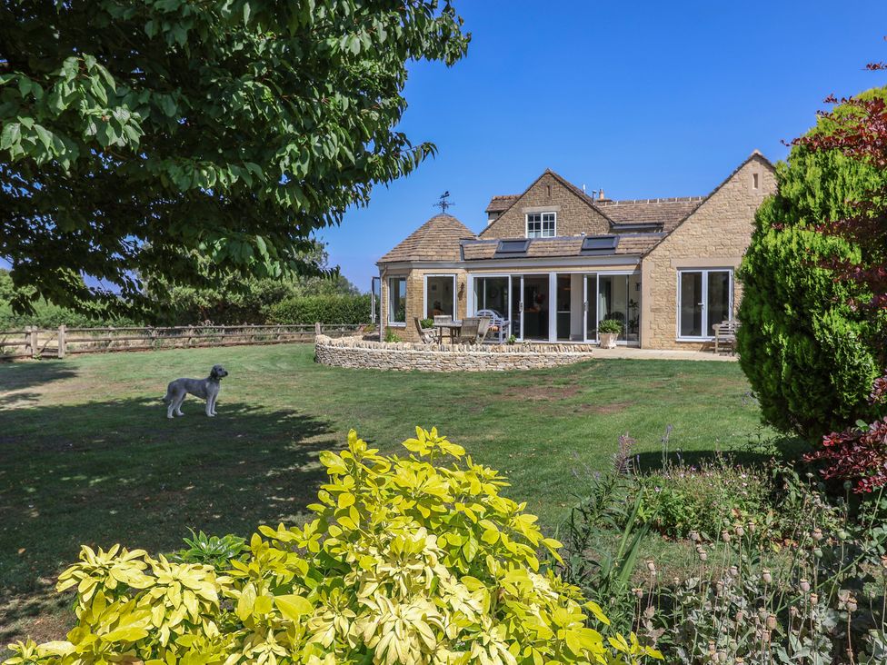 A house with a garden and a dog at Leafield Cottage in Brockworth